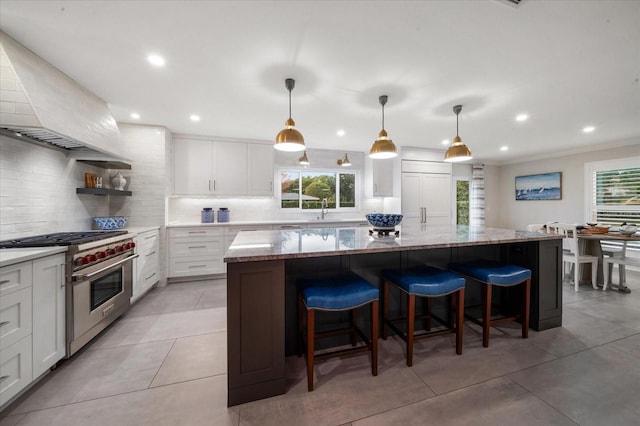 kitchen with a center island, white cabinetry, hanging light fixtures, light stone counters, and high quality appliances