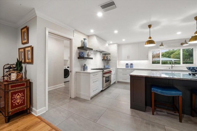 kitchen featuring high end stainless steel range oven, white cabinets, tasteful backsplash, and washer / clothes dryer