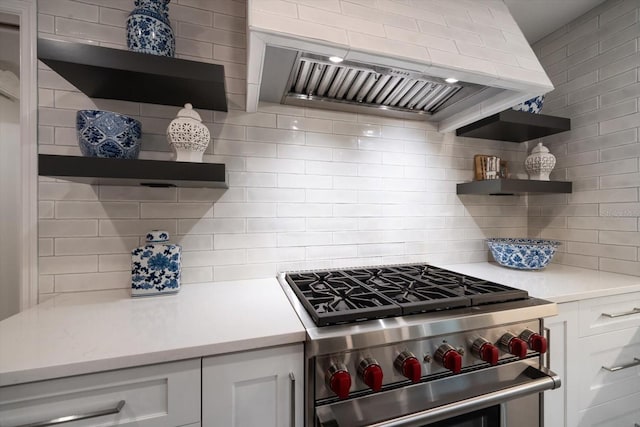 kitchen with premium range hood, white cabinetry, backsplash, and high end stainless steel range