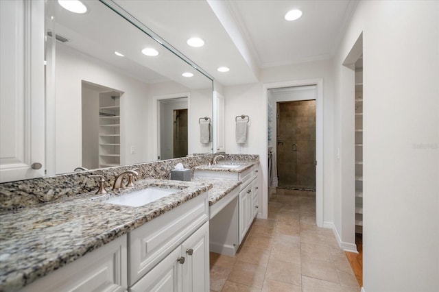 bathroom featuring vanity, ornamental molding, tile patterned flooring, and walk in shower