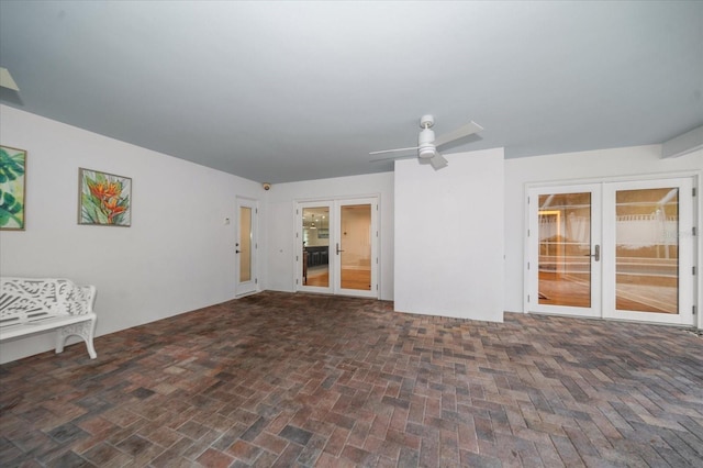 unfurnished living room featuring ceiling fan and french doors