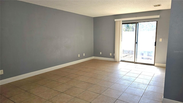 tiled empty room featuring a textured ceiling