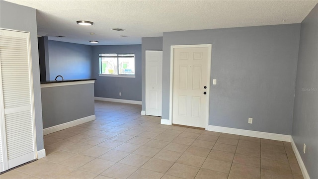 tiled empty room featuring a textured ceiling