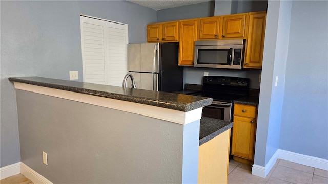 kitchen featuring a textured ceiling, appliances with stainless steel finishes, kitchen peninsula, and light tile patterned flooring