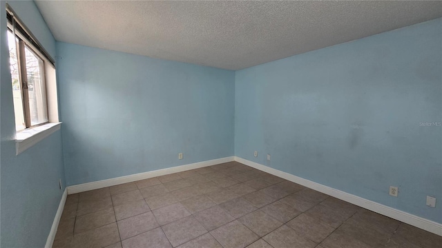 tiled empty room featuring a textured ceiling