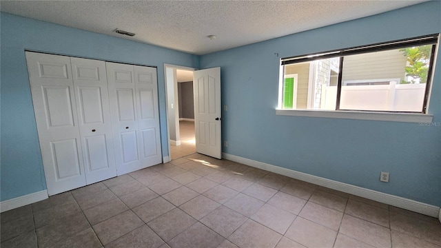 unfurnished bedroom featuring light tile patterned floors, a closet, and a textured ceiling