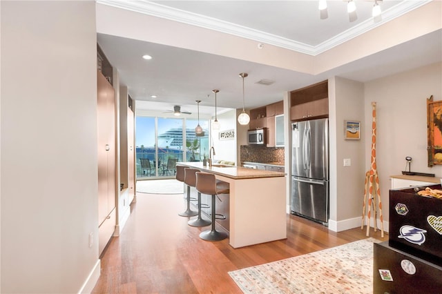 kitchen with pendant lighting, a kitchen bar, sink, appliances with stainless steel finishes, and an island with sink