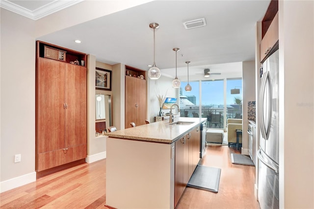 kitchen featuring decorative light fixtures, stainless steel appliances, an island with sink, sink, and ceiling fan