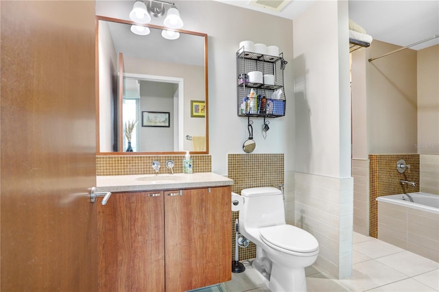 bathroom featuring tiled tub, tile patterned floors, vanity, tile walls, and toilet