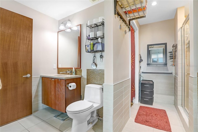 bathroom featuring toilet, tile patterned flooring, tile walls, walk in shower, and vanity