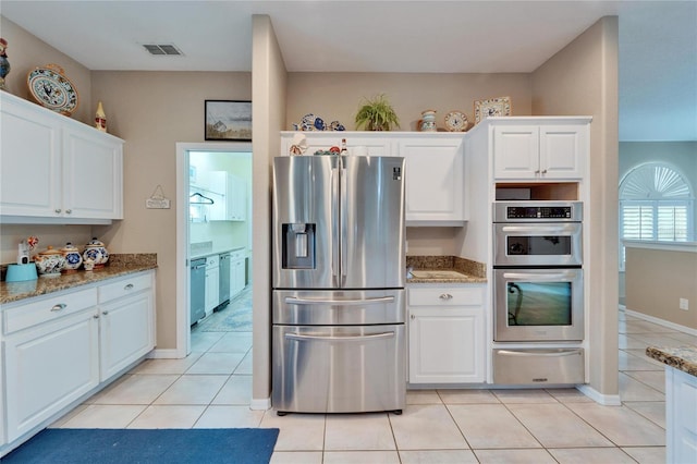 kitchen featuring light stone counters, white cabinets, appliances with stainless steel finishes, and light tile patterned floors