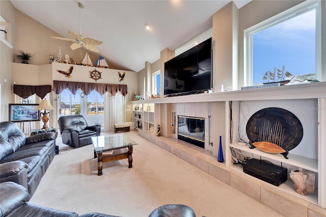 living room featuring ceiling fan, carpet, high vaulted ceiling, and a tiled fireplace