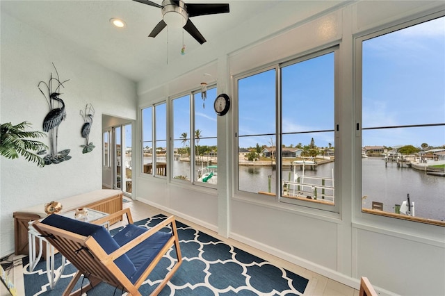 sunroom / solarium with ceiling fan and a water view