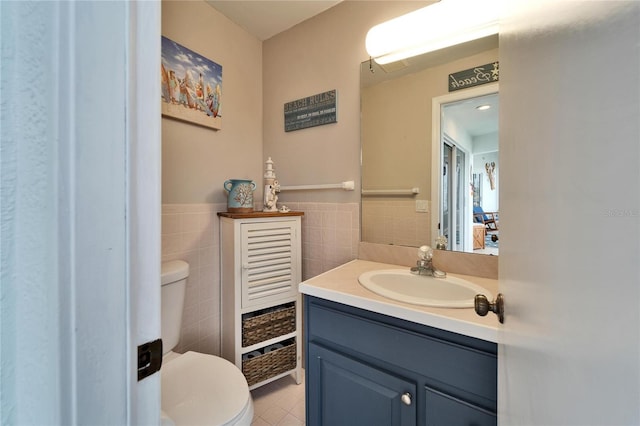 bathroom featuring toilet, tile patterned flooring, vanity, and tile walls