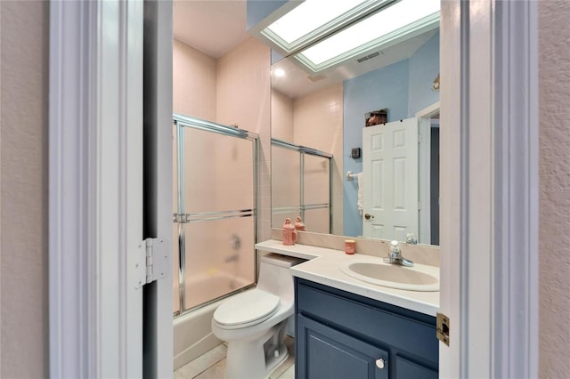 full bathroom with toilet, vanity, a skylight, and combined bath / shower with glass door