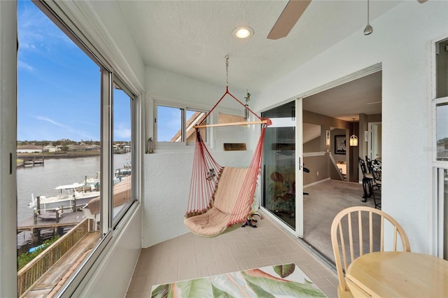 sunroom / solarium featuring ceiling fan and a water view