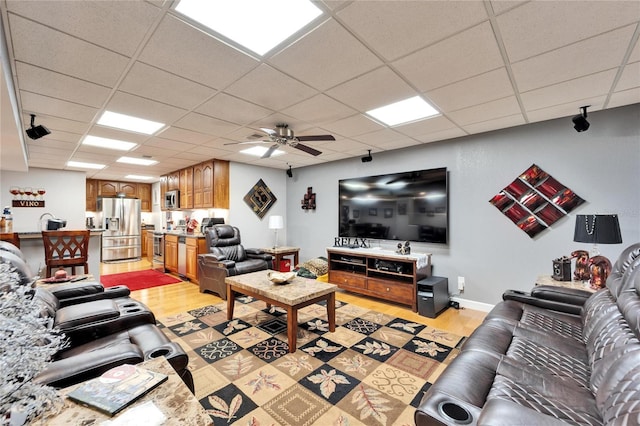 living room with light hardwood / wood-style floors, a paneled ceiling, and ceiling fan