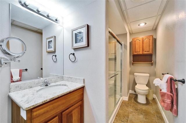 bathroom with vanity, toilet, an enclosed shower, and a drop ceiling