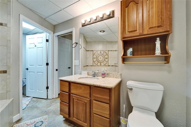 bathroom with a drop ceiling, toilet, and vanity