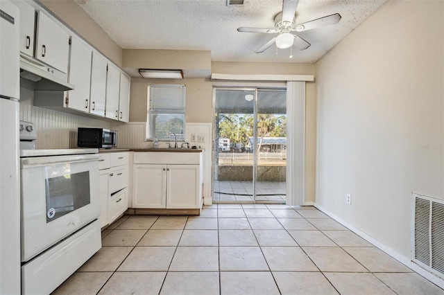 kitchen featuring light tile patterned floors, electric range, white cabinets, and a textured ceiling