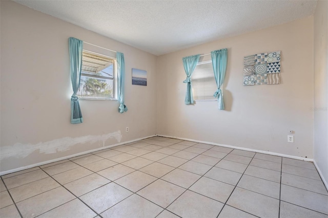 unfurnished room with a textured ceiling and light tile patterned flooring