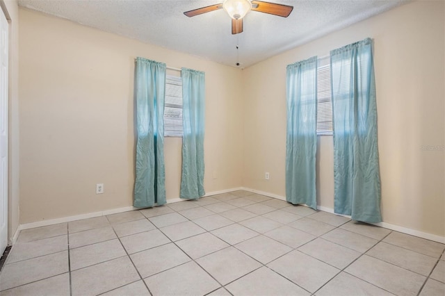 spare room featuring a textured ceiling, ceiling fan, and light tile patterned flooring