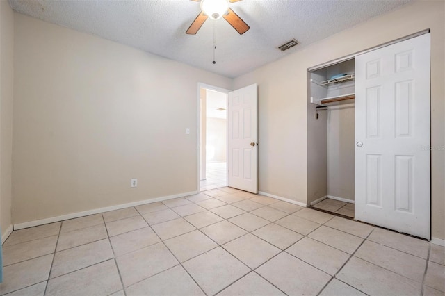 unfurnished bedroom with a textured ceiling, ceiling fan, light tile patterned flooring, and a closet