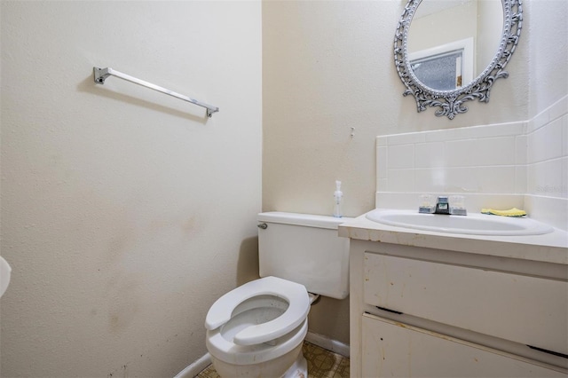 bathroom featuring toilet, decorative backsplash, and vanity