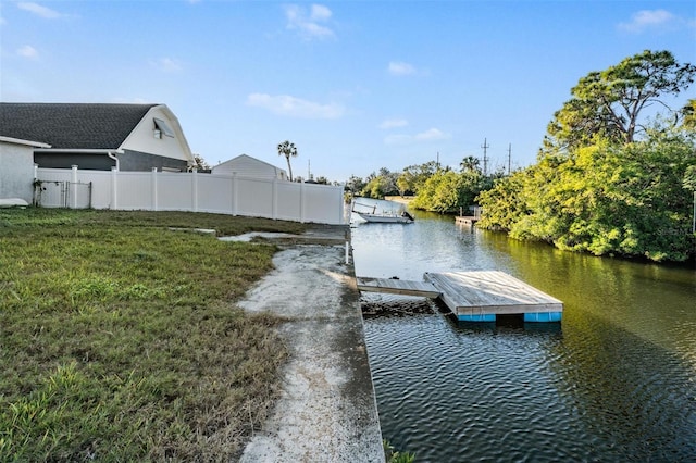 view of dock with a water view and a lawn