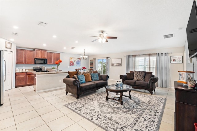 tiled living room with ceiling fan with notable chandelier