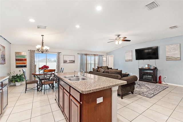 kitchen with ceiling fan with notable chandelier, lofted ceiling, sink, hanging light fixtures, and a kitchen island with sink