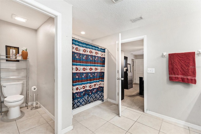 bathroom featuring toilet, tile patterned flooring, a textured ceiling, and walk in shower