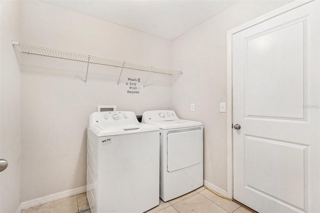 clothes washing area featuring washer and dryer, a textured ceiling, and light tile patterned flooring