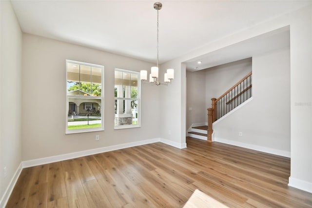 unfurnished dining area with wood-type flooring and a notable chandelier