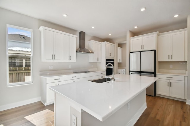 kitchen featuring sink, white cabinetry, a center island with sink, and wall chimney exhaust hood