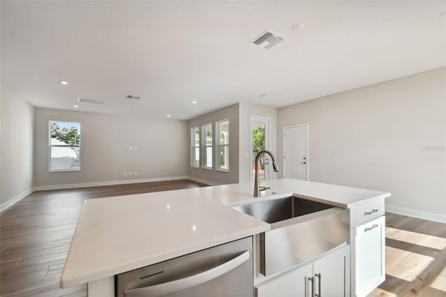 kitchen featuring white cabinets, dishwasher, light hardwood / wood-style floors, sink, and a center island with sink