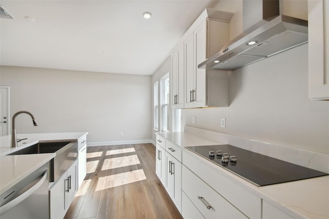 kitchen featuring white cabinets, wall chimney exhaust hood, sink, stainless steel dishwasher, and black electric cooktop