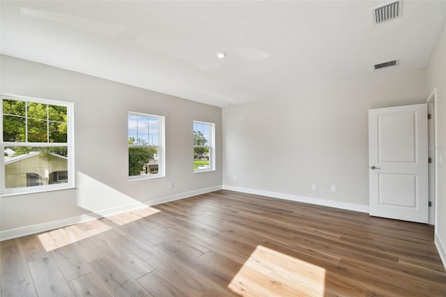 empty room with hardwood / wood-style floors and a healthy amount of sunlight