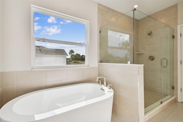 bathroom with tile patterned flooring, tile walls, and shower with separate bathtub