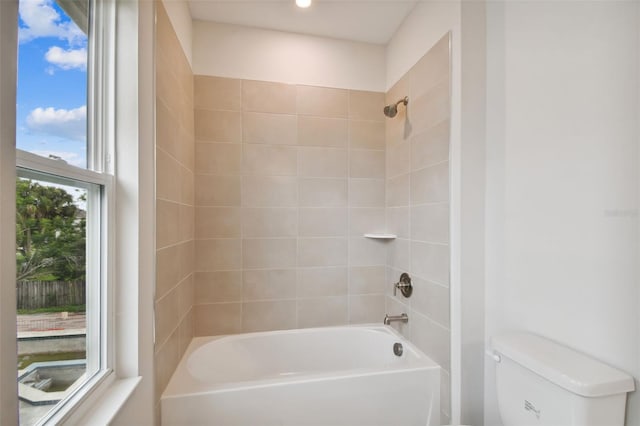 bathroom featuring toilet, tiled shower / bath combo, and a wealth of natural light