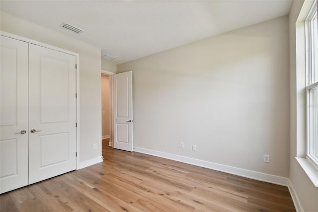 unfurnished bedroom with light wood-type flooring and a closet