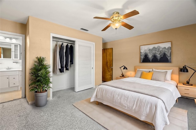 bedroom featuring ceiling fan, sink, ensuite bathroom, and a closet