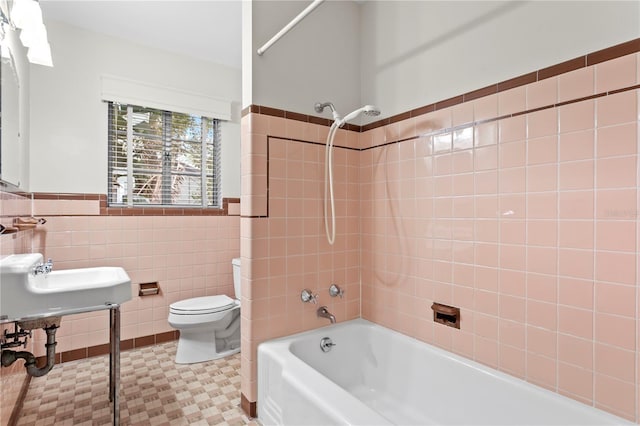 bathroom featuring toilet, tiled shower / bath, tile walls, and tile patterned floors