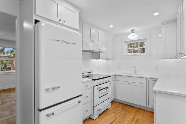 kitchen featuring a wealth of natural light, white cabinets, sink, and white appliances