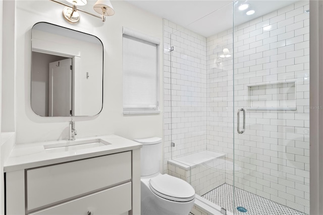 bathroom with a shower with shower door, toilet, and vanity