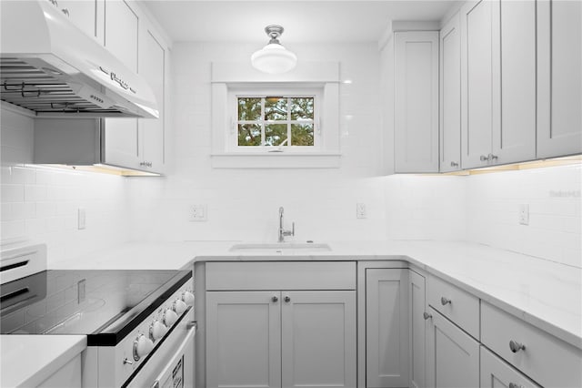 kitchen with backsplash, stainless steel electric range, white cabinets, light stone counters, and sink