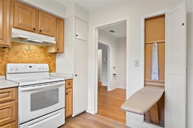 kitchen with tasteful backsplash, white electric stove, and light hardwood / wood-style flooring