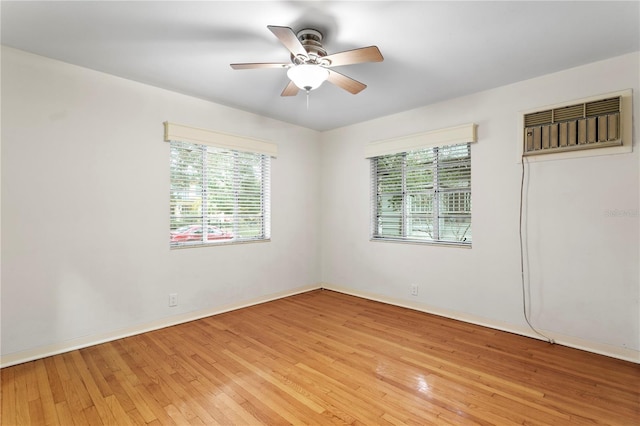 spare room featuring ceiling fan, light wood-type flooring, a wealth of natural light, and a wall mounted air conditioner