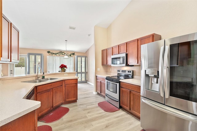 kitchen with pendant lighting, appliances with stainless steel finishes, lofted ceiling, light hardwood / wood-style floors, and sink