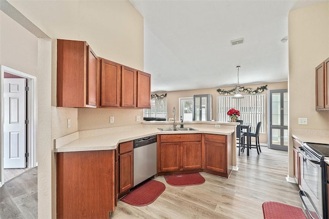 kitchen with light hardwood / wood-style floors, sink, kitchen peninsula, pendant lighting, and stainless steel appliances